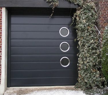 porte de garage noire avec des hublots ronds en inox